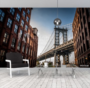 Picture of Manhattan bridge seen from a narrow alley enclosed by two brick buildings on a sunny day in summer
